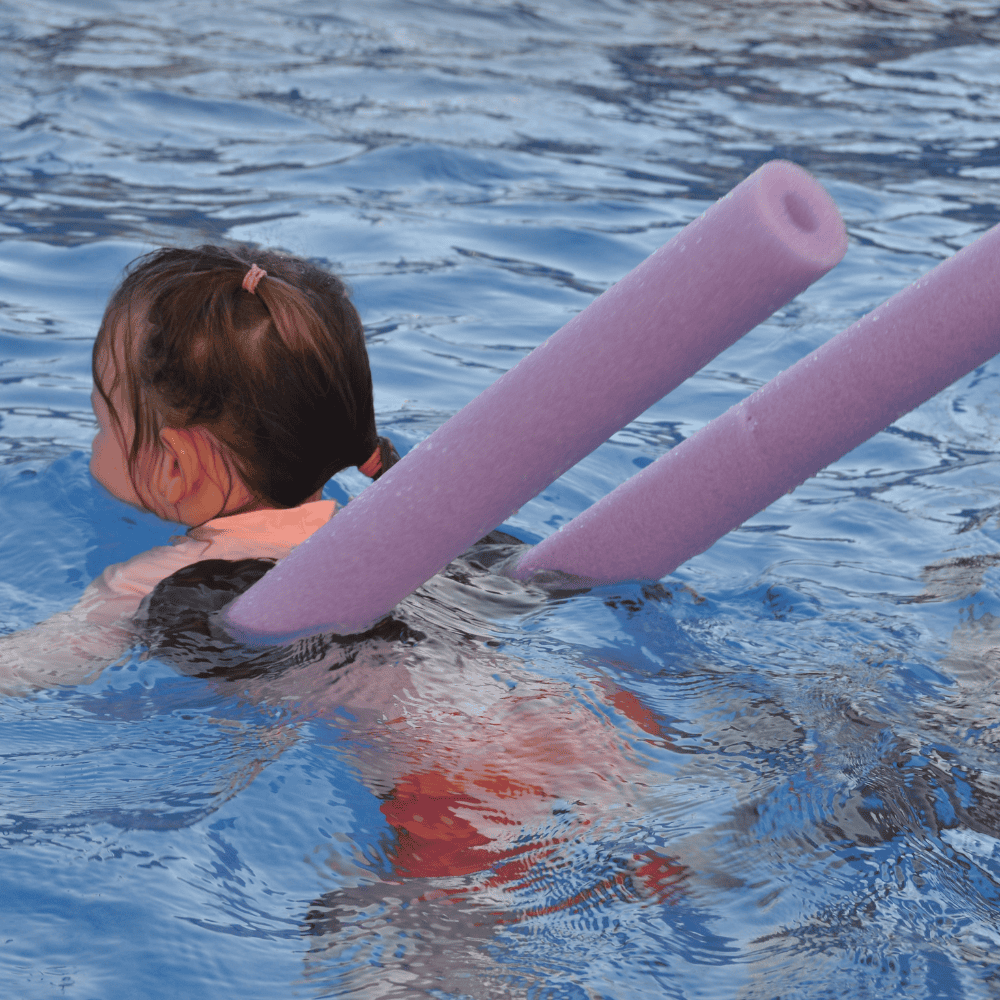 Niña con conector para churro de piscina Criaturas Infinitas